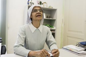 Foto de freira falando, em um ambiente de escritório.