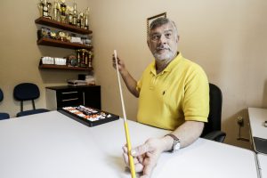 Foto de homem sentado em escritório segurando uma bengala sobre a mesa.