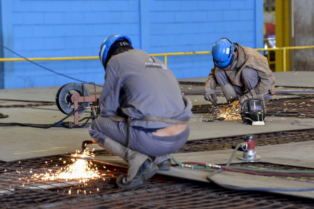 Foto de dois trabalhadores da indústria siderúrgica no Estaleiro Atlântico Sul.