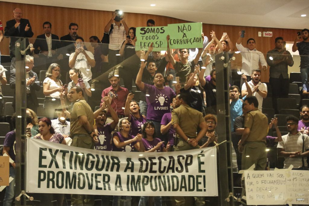 Foto de galerias do Plenário Eduardo Campos mostrando cartazes contra a extinção da Decasp e grande quantidade de pessoas.