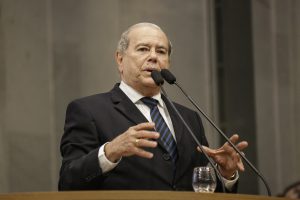 Foto de Romário Dias falando ao microfone da tribuna da Alepe.