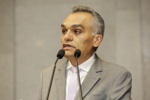 Foto de Odacy Amorim falando ao microfone na tribuna.