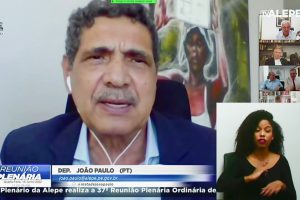 Deputado fala em reunião plenário, com quadro represetnando uma trabalhadora negra ao fundo