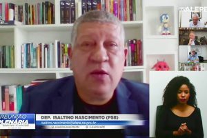 Deputado falando em reunião plenária virtual, com estante de livros ao fundo
