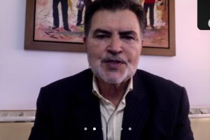 Foto de parlamentar em reunião online da Alepe, com quadro ao fundo