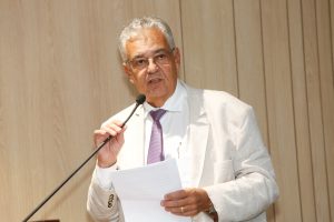 Deputado, de terno branco, fala ao microfone do Auditório Sérgio Guerra