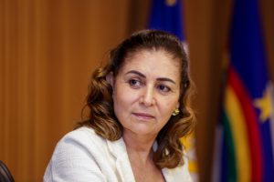 Deputada Simone Santana, usando blazer branco, com bandeira de Pernambuco ao fundo