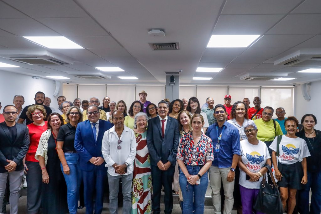 Com o deputado João Paulo ao centro, participantes da audiência posam para a foto de pé, nas cadeiras do auditório.