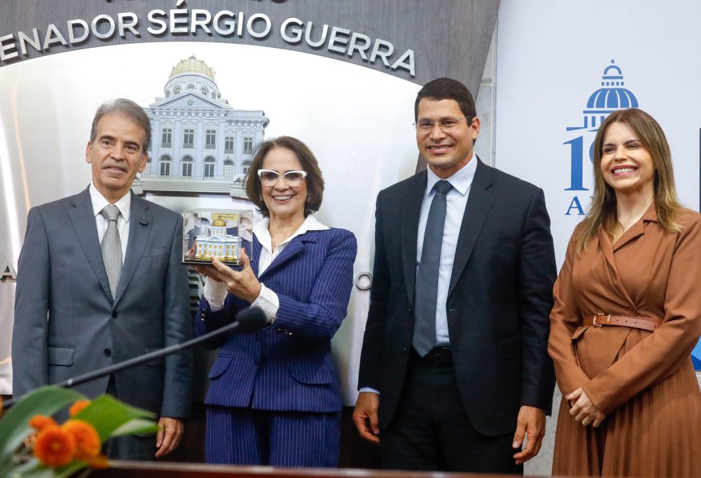 Da esquerda para direita, aparecem na foto Coronel Alberto Feitosa, Damares Alves, Pastor Junior Tercio e Clarissa Tercio. Damares Alves segura uma miniatura do Palácio Joaquim Nabuco, e por trás dela aparece um painel com o nome "Auditório Sergio Guerra" e uma ilustração do Palácio