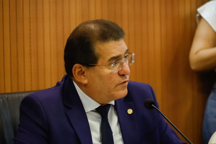 Deputado Luciano Duque, um homem branco, de cabelo curto e usando óculos, usando um terno azul marinho com gravata preta