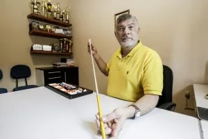Foto de homem sentado em escritório segurando uma bengala sobre a mesa.