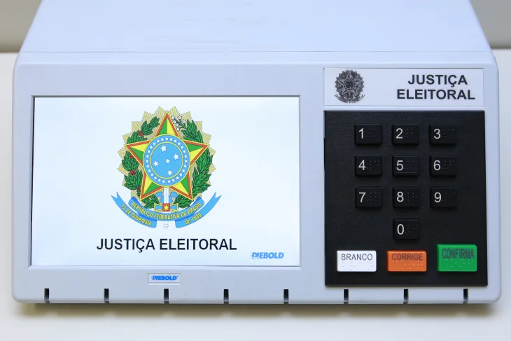 Foto da urna eletrônica, com logotipo da Justiça Eleitoral na tela